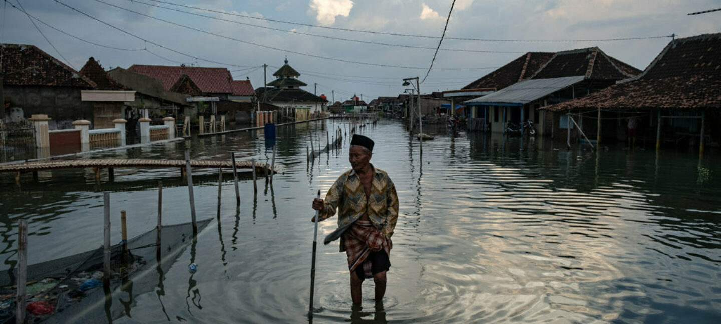Eldre mann går gjennom oversvømt gate etter flom i Indonesia