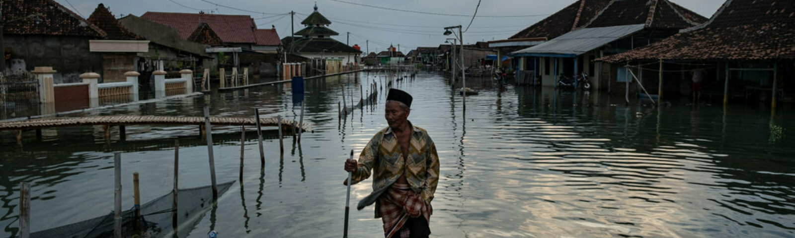 Eldre mann går gjennom oversvømt gate etter flom i Indonesia.