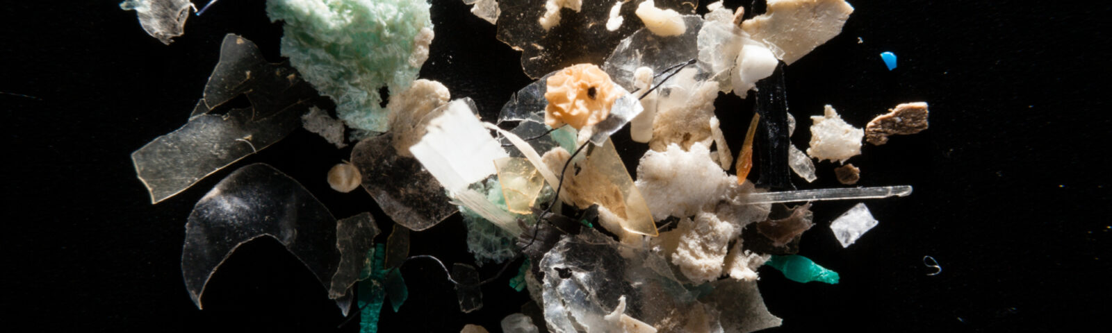 Nærbilde av ulike former og farger av mikroplast på sort bakgrunn