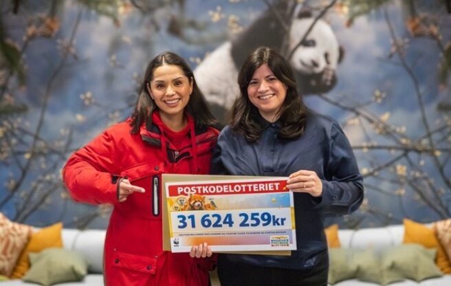 Generalsekretær i WWF Karoline Andaur, og Jorun Stiansen fra Postkodelotteriet holder en stor sjekk og smiler.