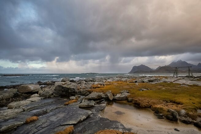 Norsk kystlinje der man ser fjord og fjell, med uværsskyer i bakgrunnen.